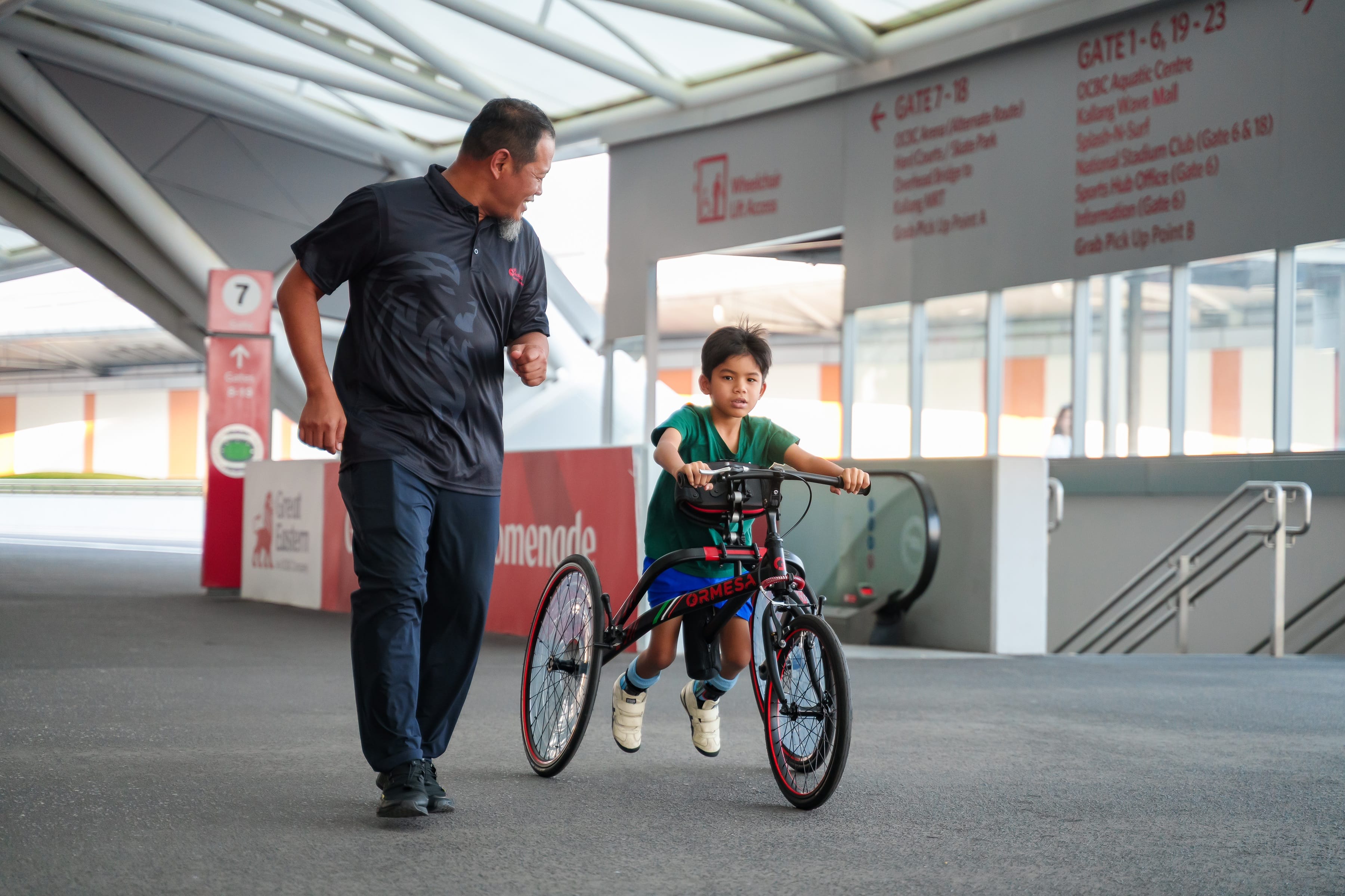 An older man running alongside a young boy on his frame running equipment